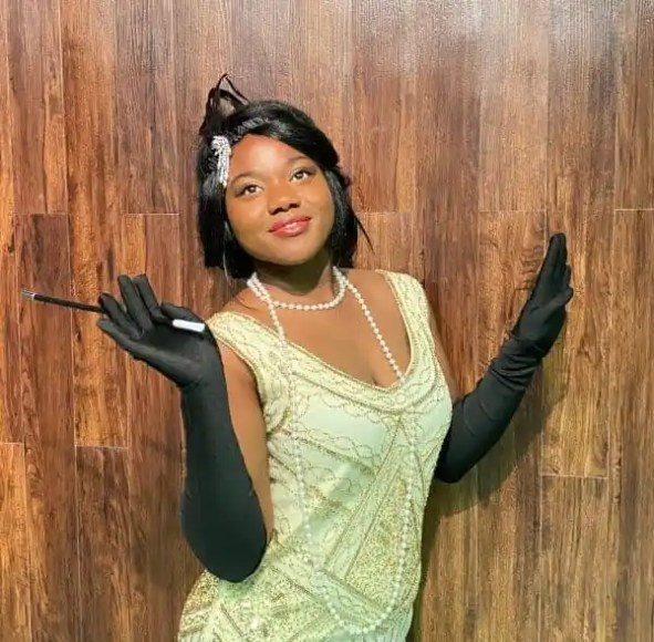 A performer in a glamorous outfit poses with a pen and black gloves. Rigatonysclarion Riga Tony S Branson Murder Mystery Dinne Dinner Show Performer Glamorous Costum