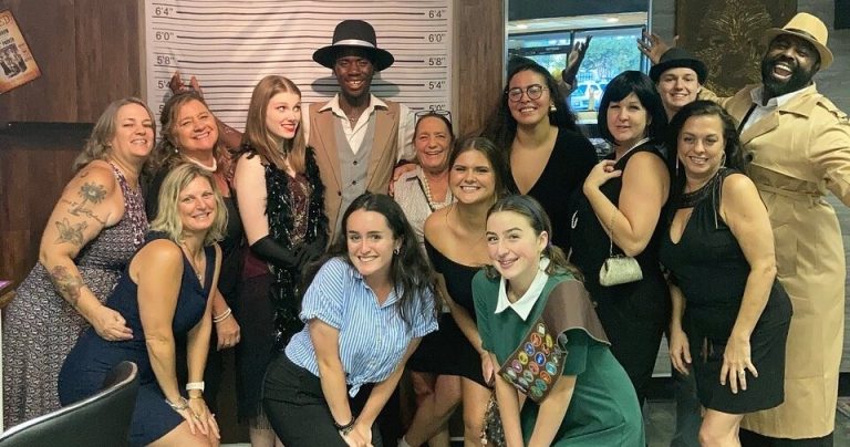 A group of people in costumes posing for a photo at a dinner show. Rigatonysclarion Riga Tony S Branson Murder Mystery Dinne Murder Mystery Dinner Show Group Costu