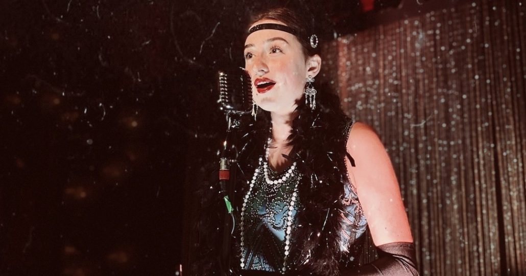 A singer in a vintage dress performs with a microphone. Rigatonysdinnershow Christmas At Myrtle Beach Singer Vintage Dress Microphone