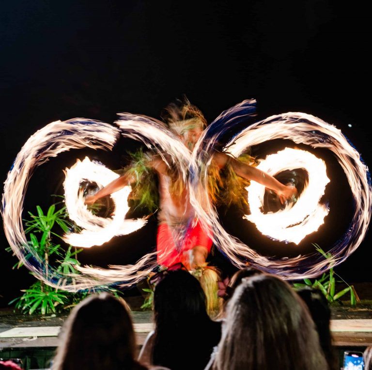 A performer spins flaming poi while dancing on stage. Royalsonestaluau Drums Dances Of Polynesia At The Royal S Fire Dancer Polynesian Luau Performanc