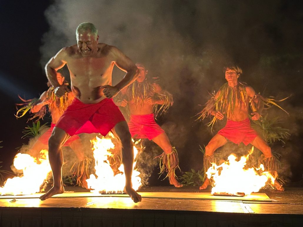 Performers in red shorts dance around flames on stage. Royalsonestaluau Drums Dances Of Polynesia At The Royal S Polynesian Dance Fire Performance