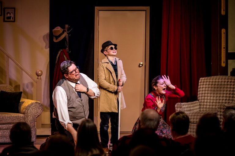 Three actors perform on stage with a door and a couch in the background. Theshepherdofthehills A Christmas Story Dinner Show Theater Performance Actors Stage