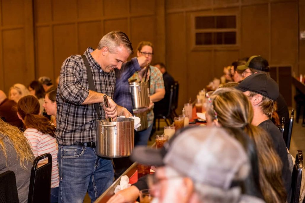 A man in a plaid shirt serves food while guests enjoy their meals. Theshepherdofthehills Branson S Whodunnit Hoedown Murder Myste Dinner Show Mystery Actors Audien