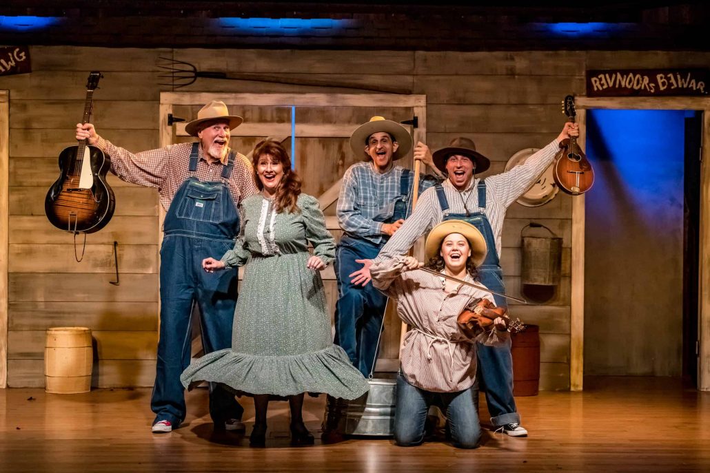 Five performers in costumes pose with musical instruments on stage. Theshepherdofthehills Branson S Whodunnit Hoedown Murder Myste Murder Mystery Dinner Show Perfor