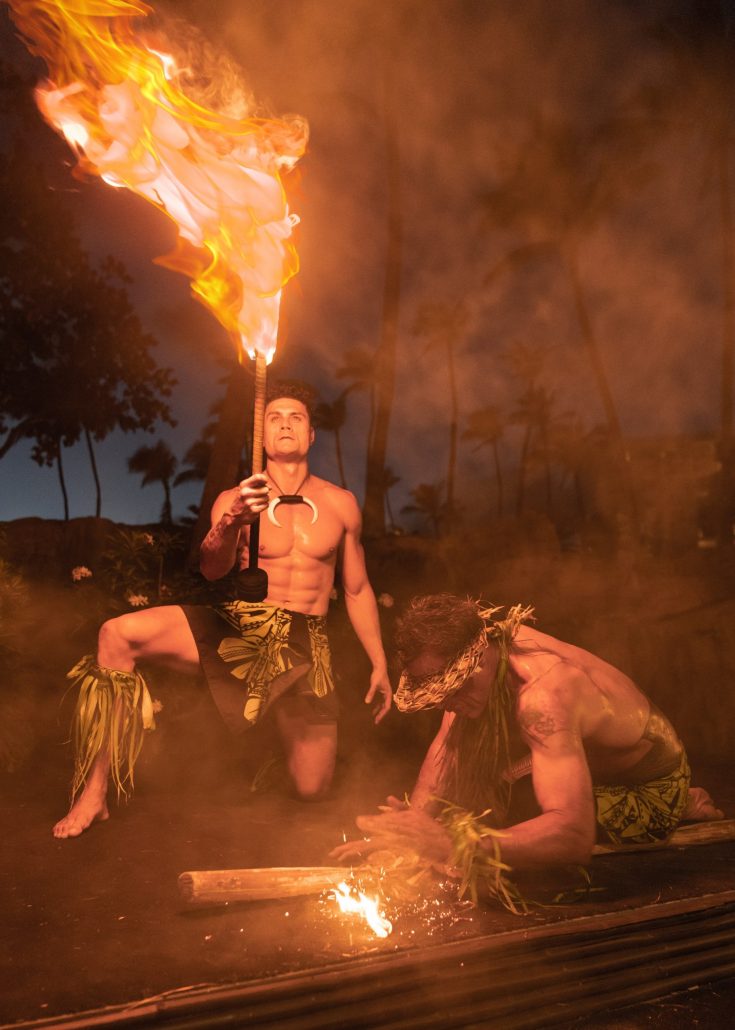 Two performers in traditional attire create fire and sparks during a luau. Westinmaui Ohana Seating Fire Dancers Luau Night Performance