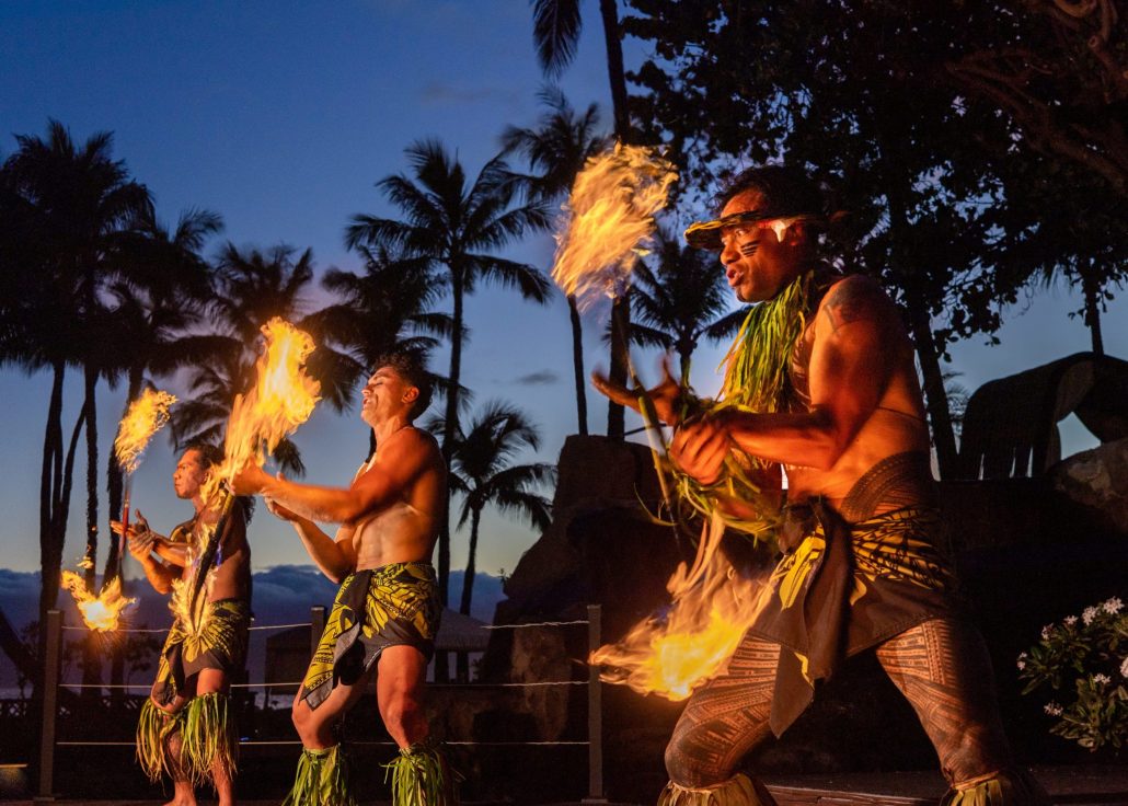 Three fire dancers perform with torches against a twilight sky and palm trees. Westinmaui Ohana Seating Fire Dancers Luau Palm Trees