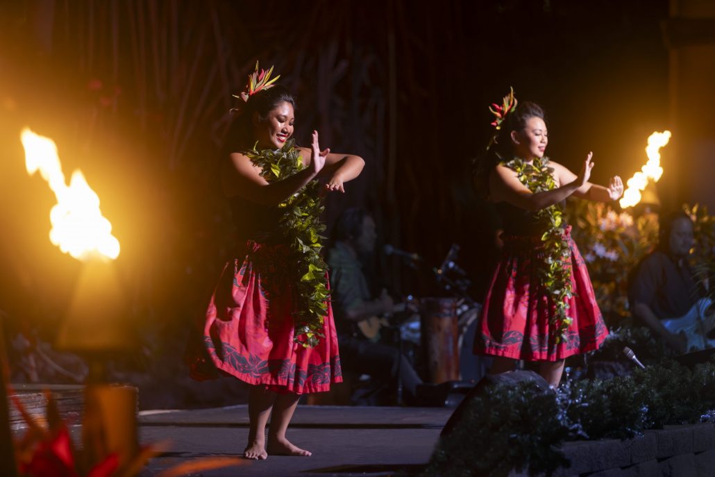 Two hula dancers perform with fire torches in a vibrant setting. Westinmaui Ohana Seating Hula Dancers Flame Performance